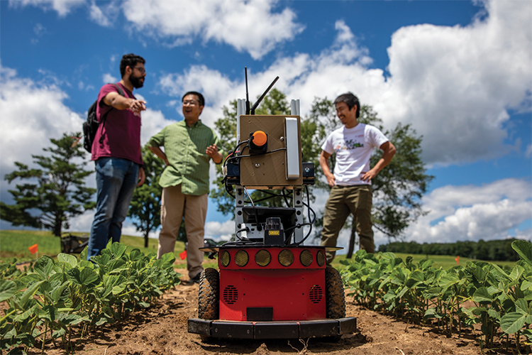 Image of three students and a robot in a field