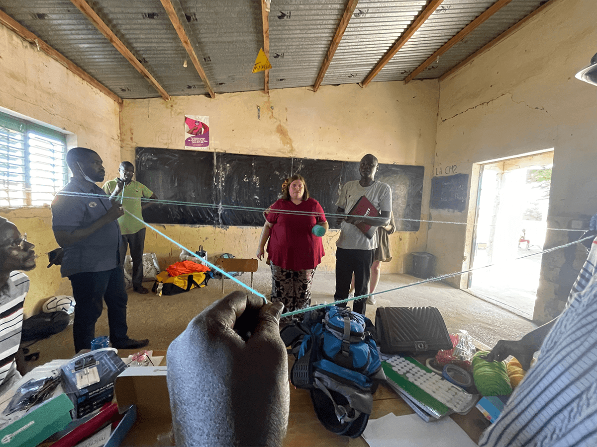 Extension agent helping teach about how to grown mung beans, explaining how to measure with string