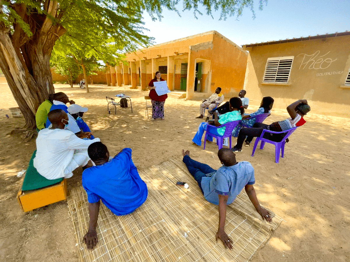 Erika Bonnett teaching a group of Senagalese villagers under a tree
